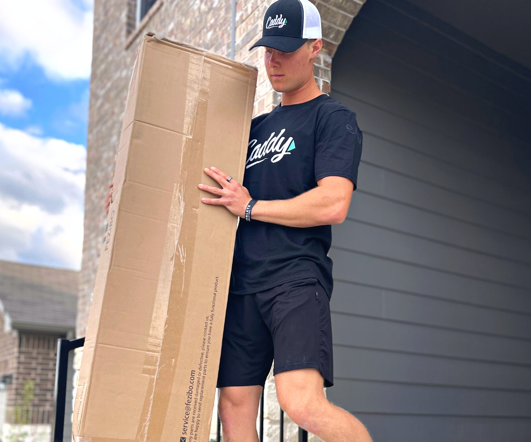 Zach the Caddy Mover helping move a big vertical box out of a family home in the suburbs