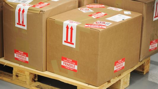 Boxes on a wooden skid. The boxes are heavily marked up with fragile and handling stickers