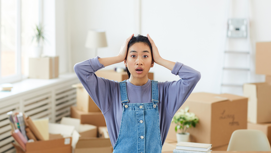 Young lady shocked and overwhelmed by moving stuff, thinking how to get things done without getting scammed by a labor-only moving company