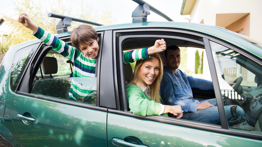 A family inside and excited for a trip, while dad is going to be the driver, mom beside her and the little boy at the back