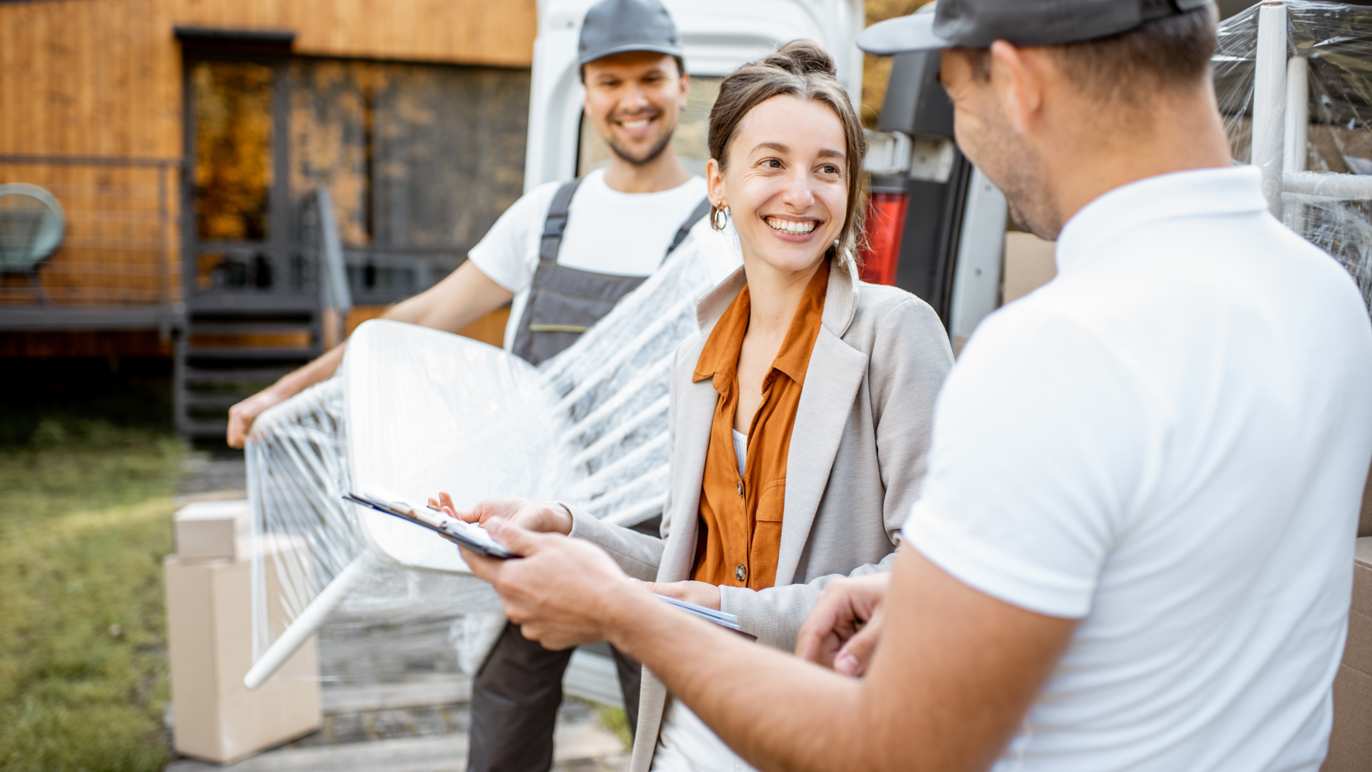 A young professional who's moving for the first time being assisted by to movers as they are moving stuff outside the truck