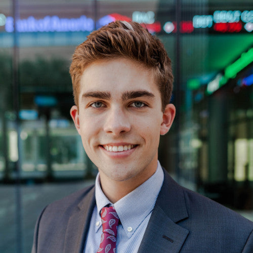 alt="A young man in a suit and tie smiles confidently, exuding professionalism and charm"