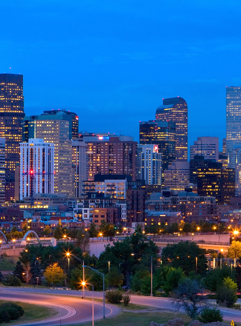 alt="A vibrant city skyline in Denver illuminated at dusk, showcasing a blend of lights against a darkening sky"