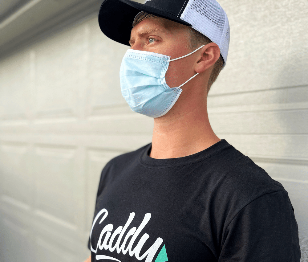 <img src=“mover covid picture.png” alt=“young mover wearing caddy moving shirt and hat looking in the distance while wearing a face mask”>
