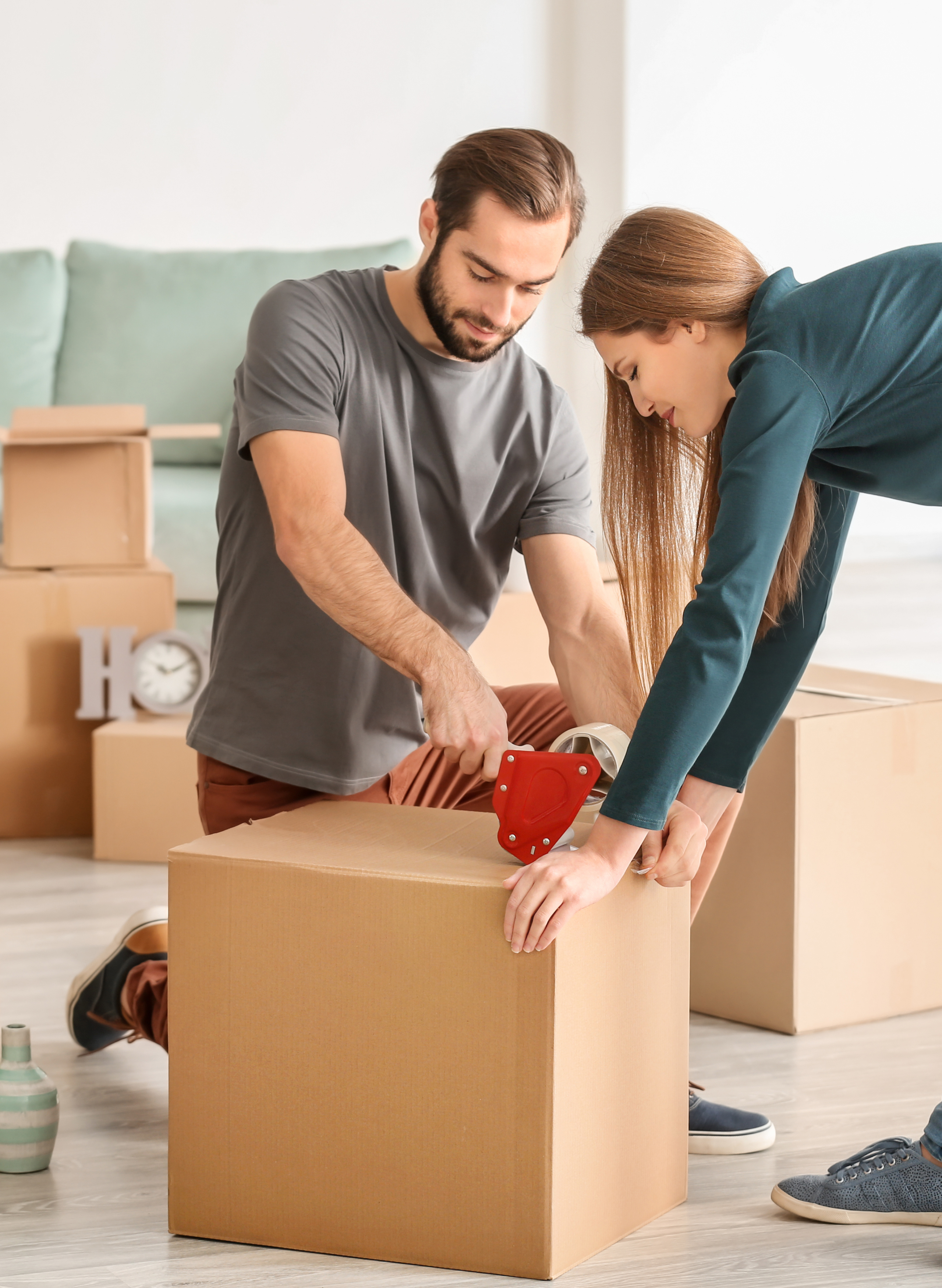 alt="a man and a woman taping together a moving box together"