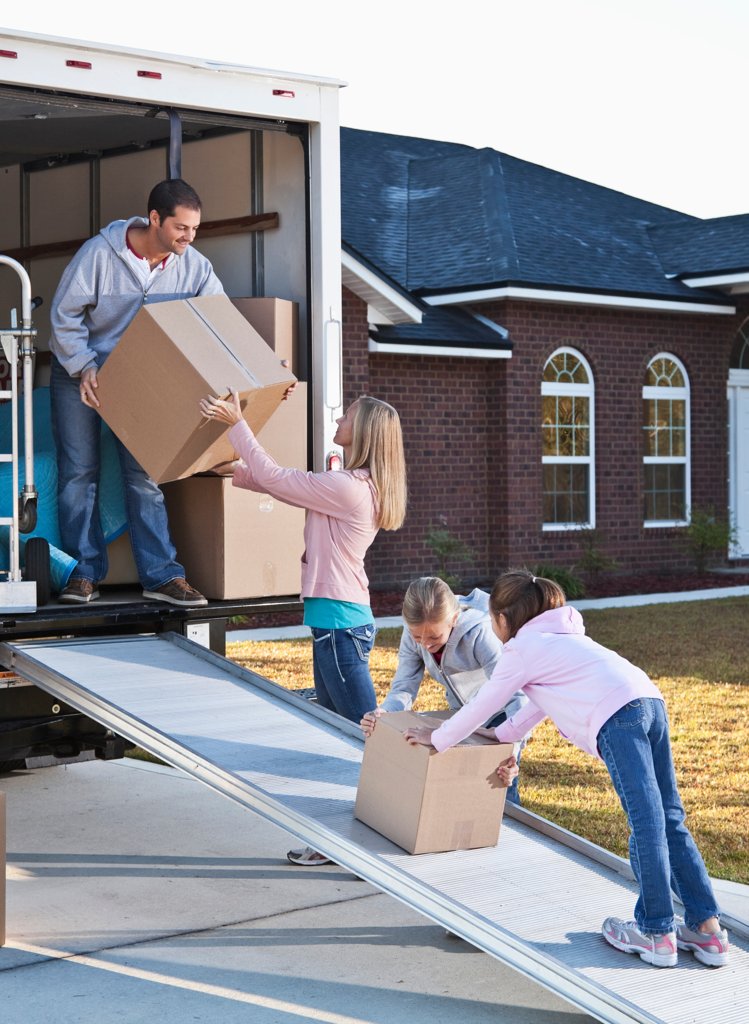 alt="a man, a woman, and their two kids helping load moving boxes into a moving truck"